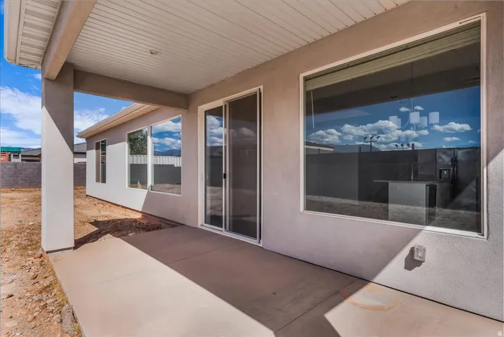 Covered patio with a concrete slab, stucco exterior, and multi-pane windows