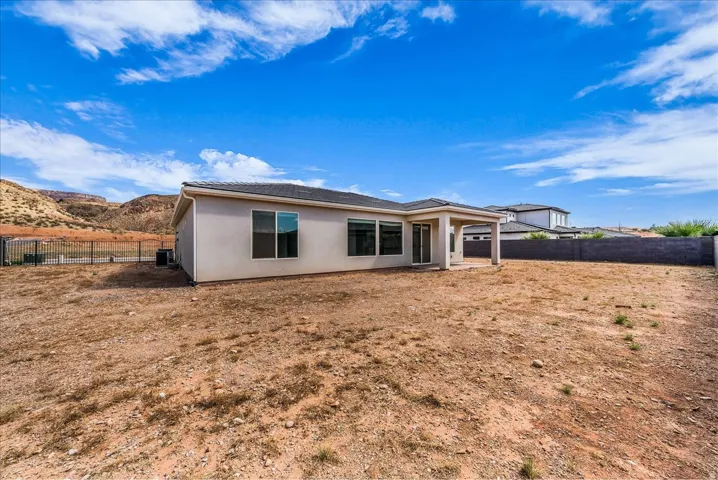 Expansive rear yard with a covered patio, multiple windows, and a walled perimeter