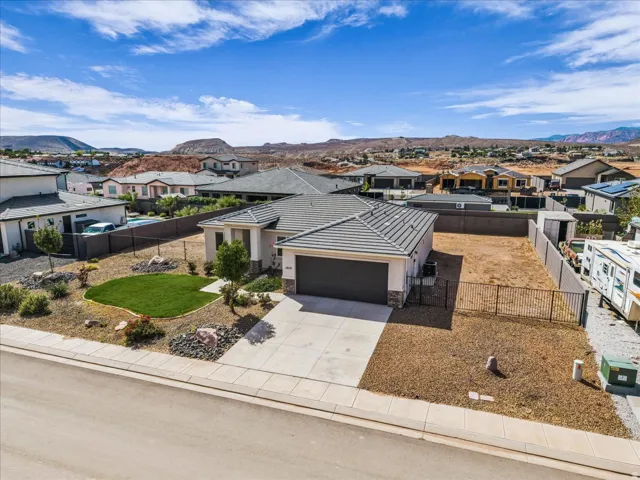 Single-story residence featuring a two-car garage, concrete driveway, and a front yard with manicured lawn and desert landscaping