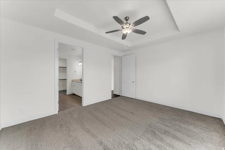 Recessed ceiling detail, ceiling fan with integrated lighting, neutral-toned carpeting, white interior doors, and clean white walls