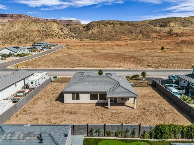 Pitched roof with gray shingles, neutral-toned exterior, covered patio, and substantial surrounding land