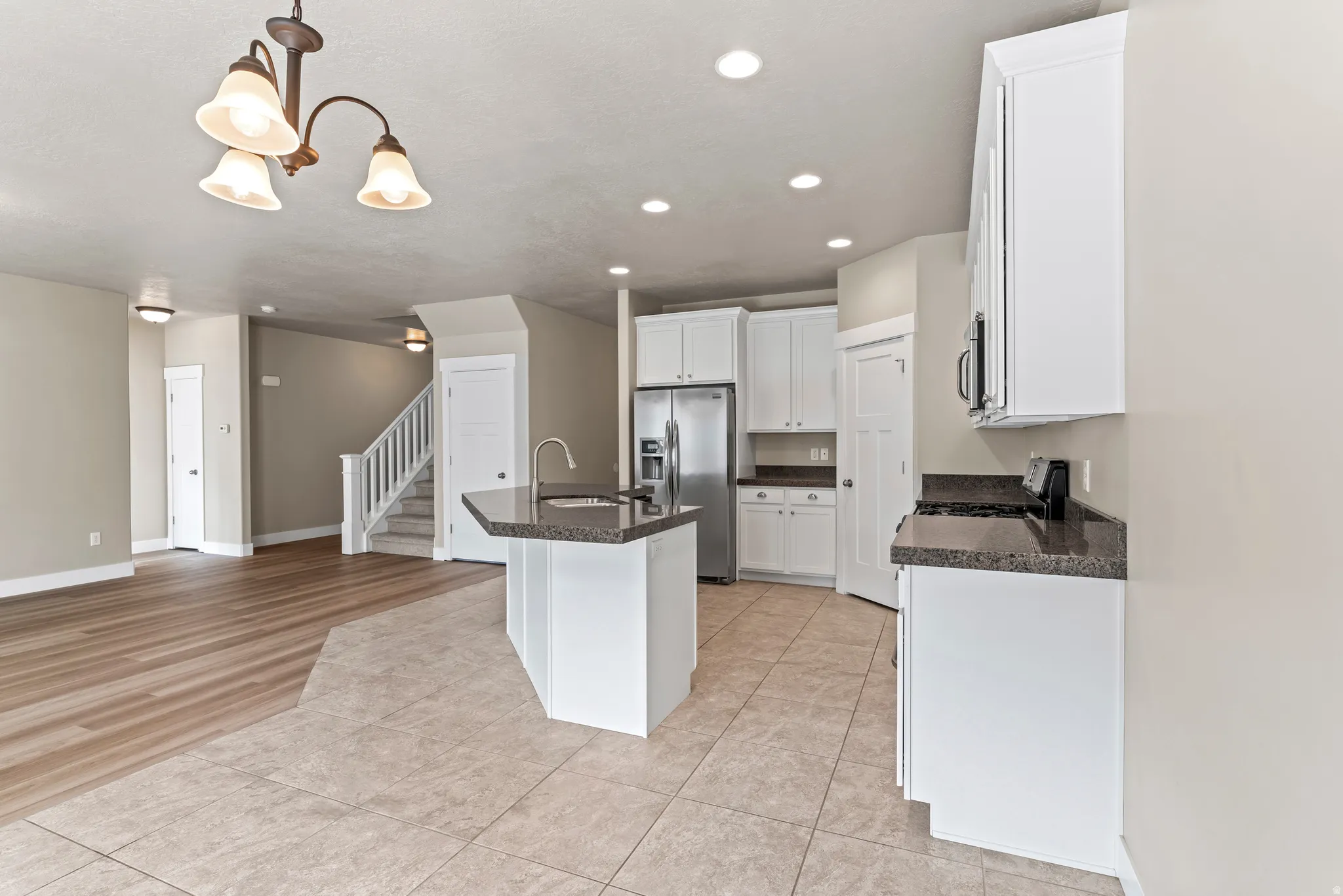 Kitchen featuring white cabinetry, dark stone countertops, a stainless steel refrigerator, and recessed lighting