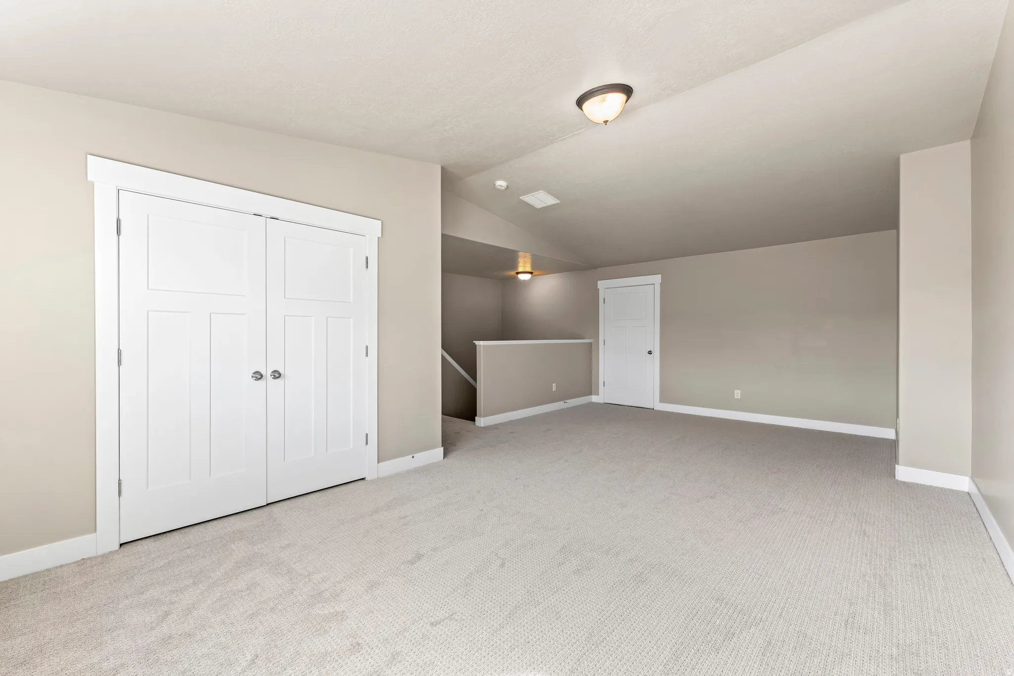 Spacious room featuring neutral carpeting, light neutral wall paint, white trim, and a built-in closet with panel doors