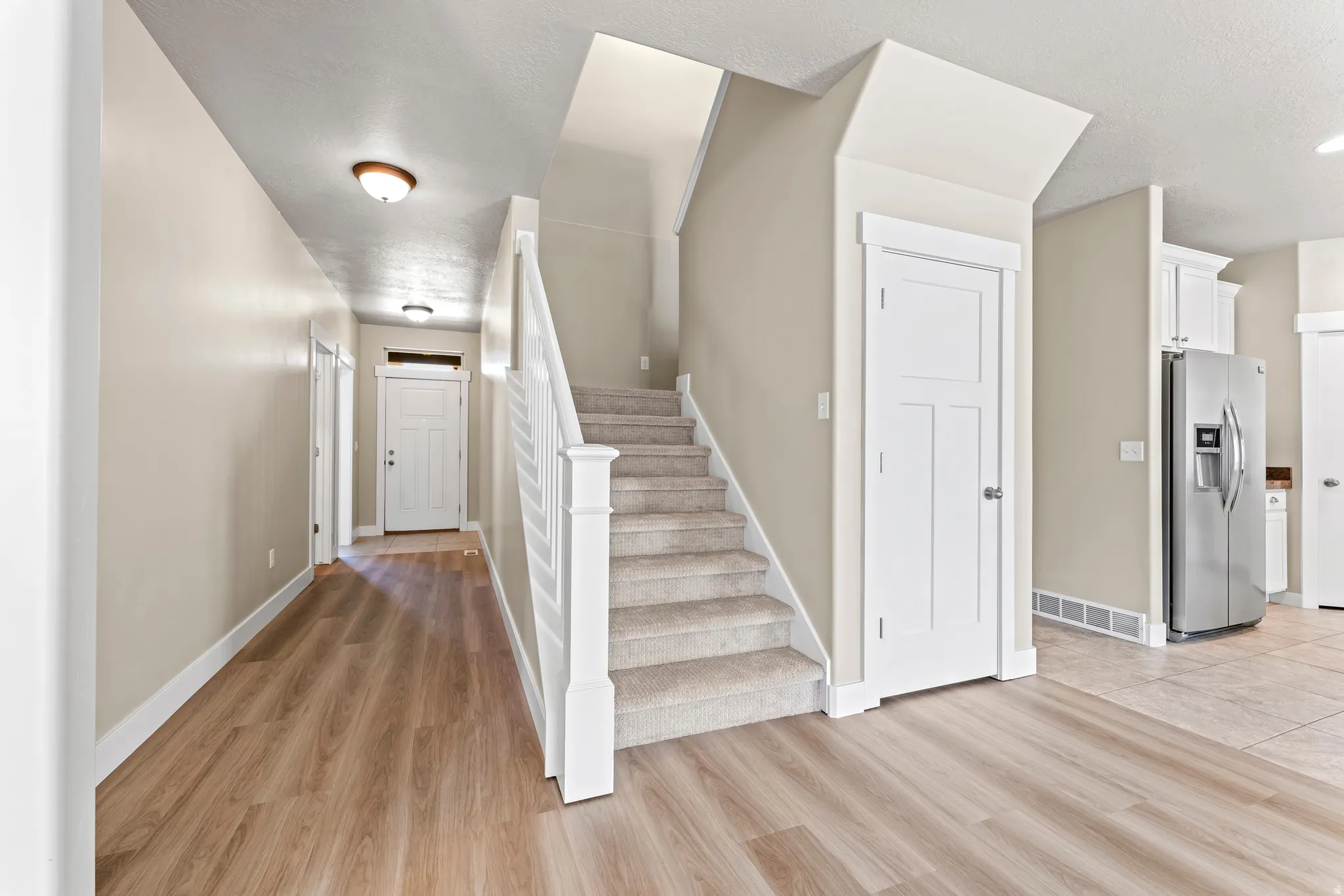 Entryway featuring wood-finish flooring, a carpeted staircase with white railings, and recessed lighting