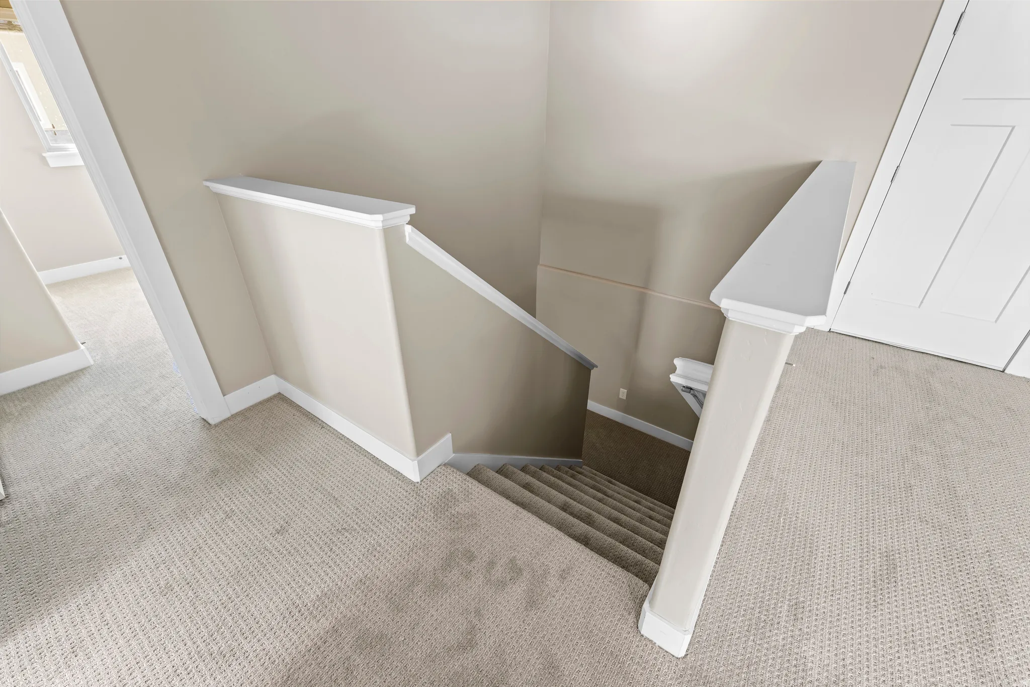Carpeted staircase with painted risers, solid balustrade, and neutral wall tones