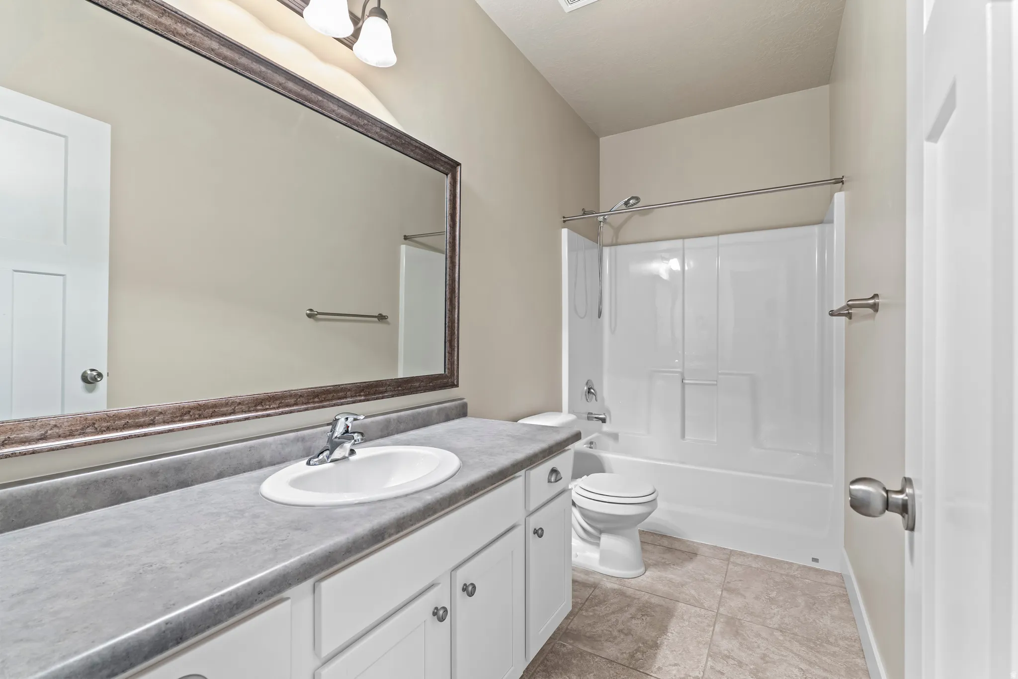 White vanity with cabinet storage, a single basin sink, and a gray countertop