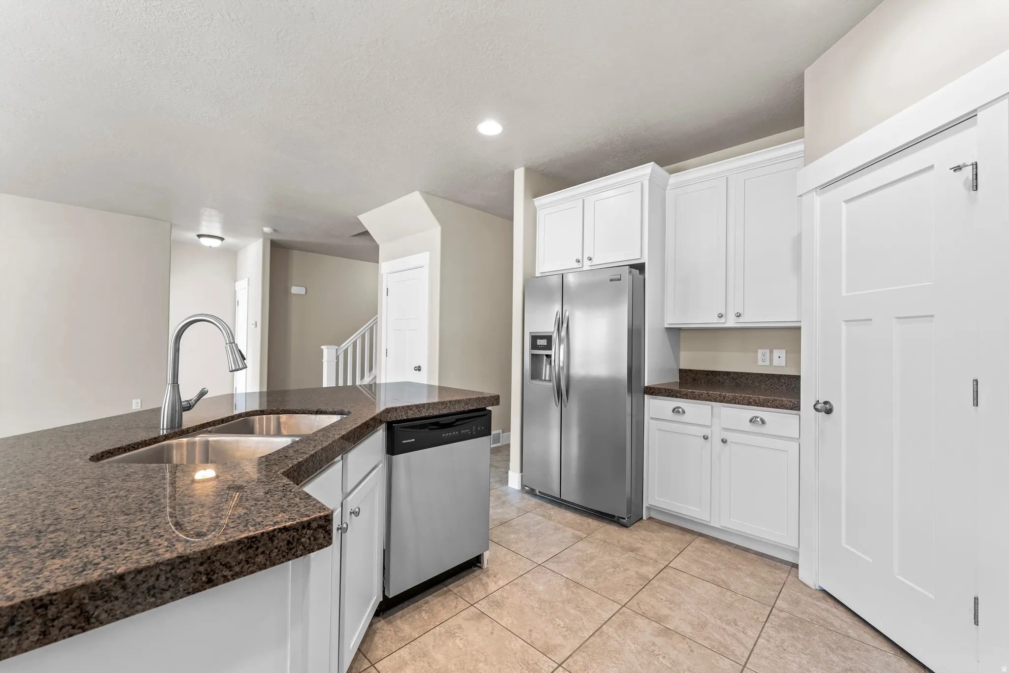 Kitchen featuring white cabinetry, stone countertops, stainless steel appliances, and tile flooring