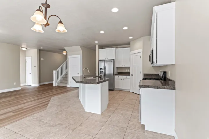 Kitchen featuring white cabinetry, dark stone countertops, a stainless steel refrigerator, and recessed lighting