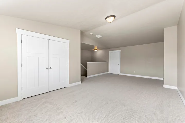 Spacious room featuring neutral carpeting, light neutral wall paint, white trim, and a built-in closet with panel doors
