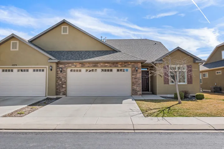 Stucco exterior with stone accents, attached two-car garage, concrete driveway, and front entryway