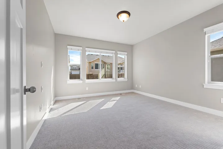 Recessed ceiling light fixture, three large windows, light grey wall paint, white trim, and carpet flooring