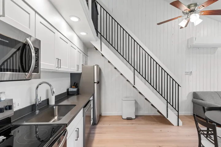 Kitchen featuring stainless steel appliances, white cabinetry, and dark countertops