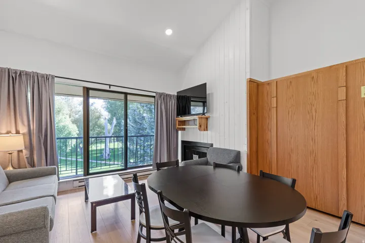 Vaulted ceiling, wood-finish flooring, full-height sliding glass doors, built-in fireplace, and wood paneling