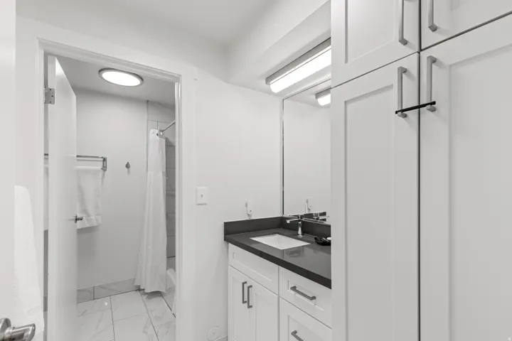 White vanity with under-mount sink, dark countertop, and brushed nickel fixtures