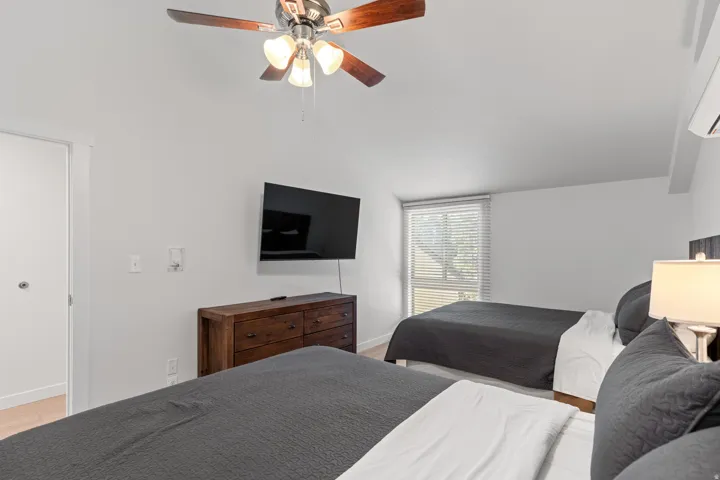 Vaulted ceiling with a ceiling fan, wall-mounted television, and light wood-finish flooring