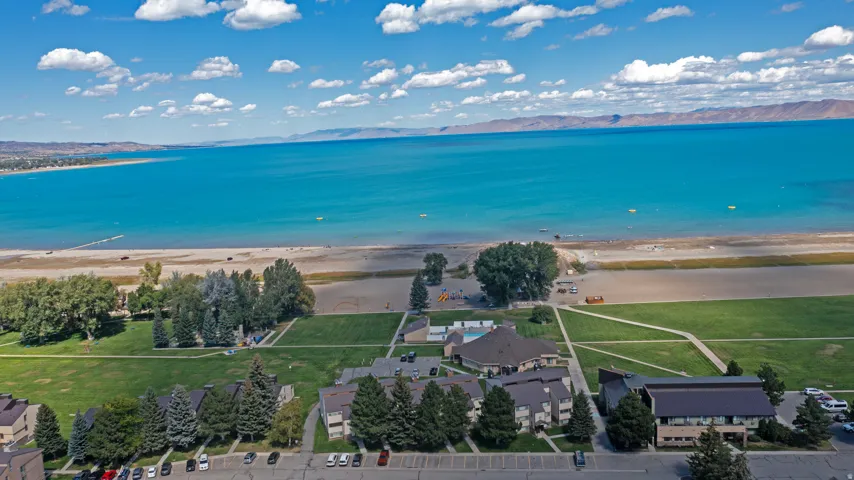 Lakeside community featuring multiple residential structures, expansive green spaces, and an outdoor swimming pool