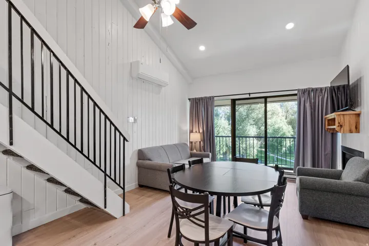 Vaulted ceilings with a ceiling fan, light wood-finish flooring, and white vertical plank walls