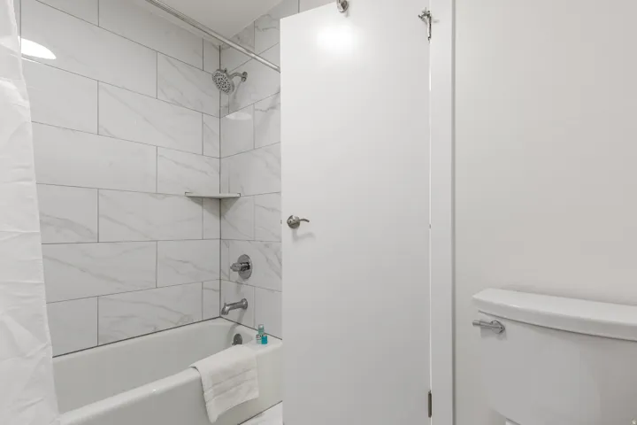 Bathtub with subway tile surround, chrome showerhead, and integrated corner shelf