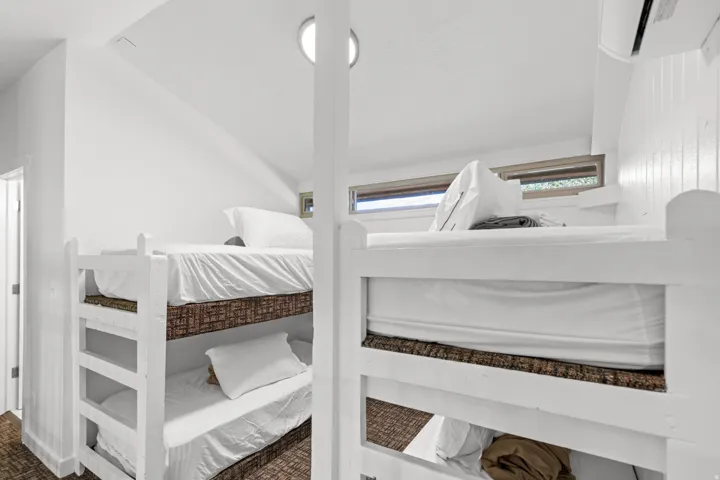 Built-in bunk beds with white frames, upper windows, and recessed ceiling lights