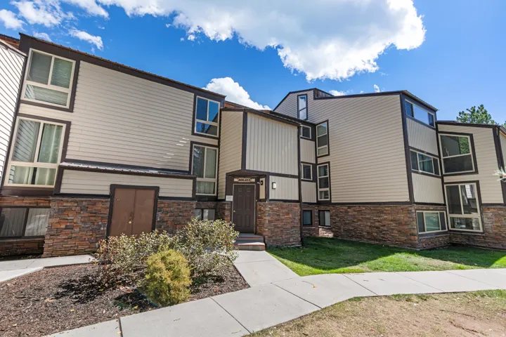 Multi-level exterior featuring light-colored siding, dark trim, and stone accents