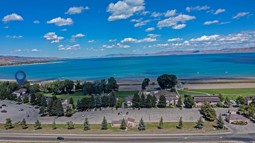 Expansive water frontage with mountain backdrop, surrounded by lush trees and broad green spaces