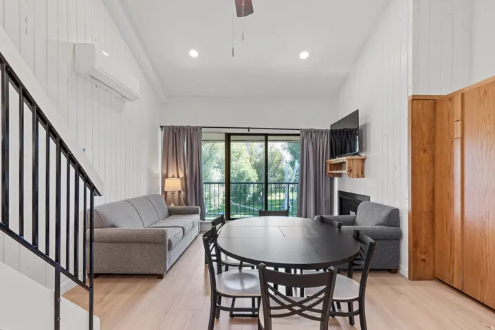 Vaulted ceiling with recessed lighting, light wood-finish flooring, white shiplap walls, built-in wooden cabinetry, and a black metal staircase railing