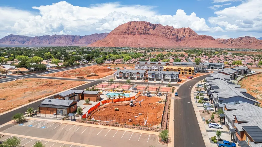 Community with desert landscaping, a central pool, tennis courts, and contemporary multi-story residences