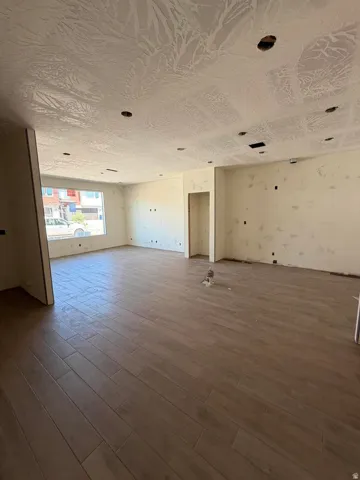 Spacious interior featuring wood-finish plank flooring, large windows, recessed lighting, and textured ceilings