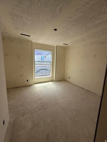 Unfinished interior space with textured ceiling, unpainted walls, and a single window