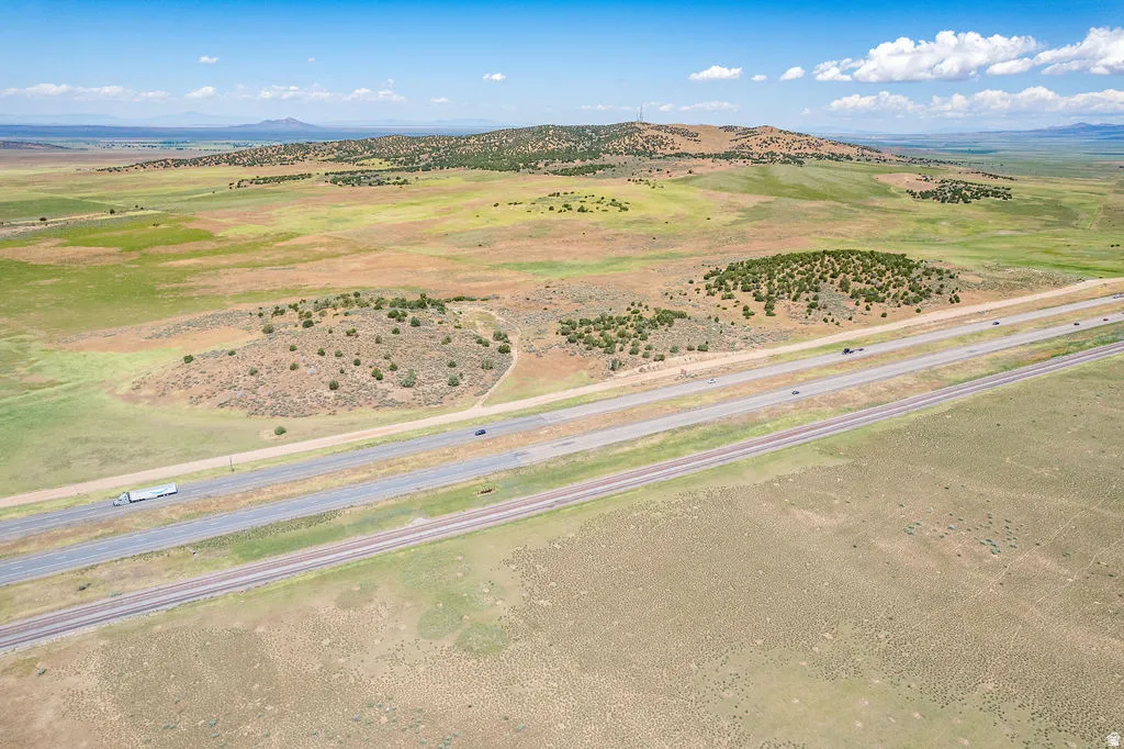 Expansive rural landscape featuring a highway, railroad tracks, and natural vegetation with distant hills