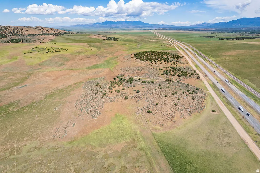 Expansive open land with varied natural ground cover and distant mountains