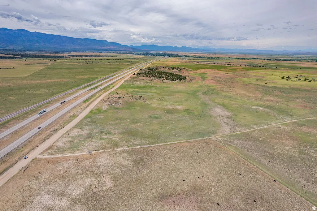 Expansive land featuring a highway, distant mountain range, and scattered vegetation