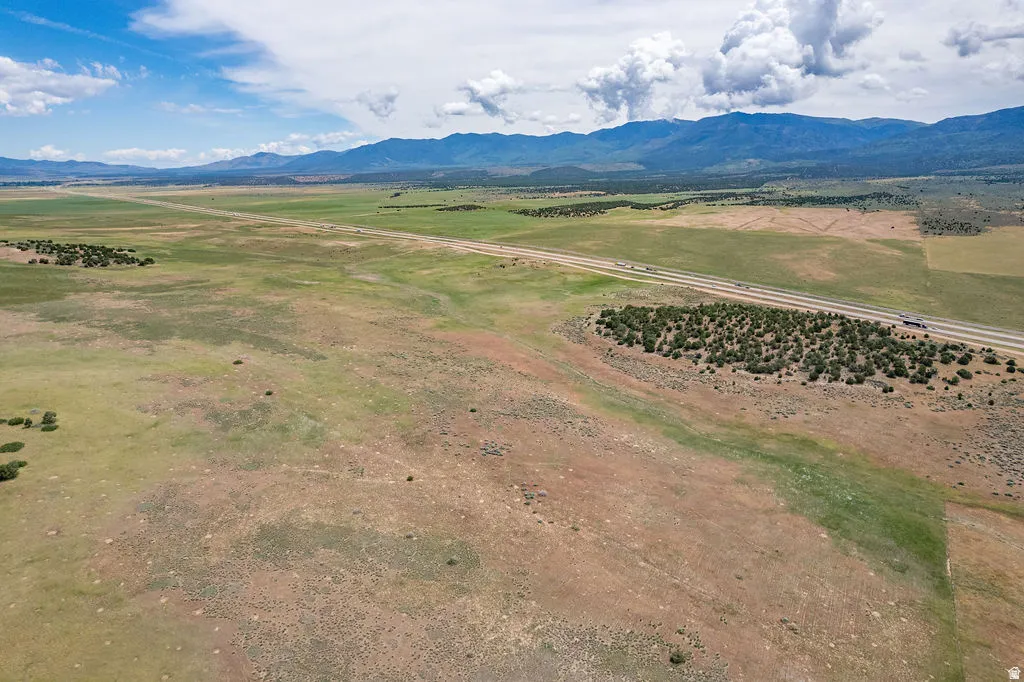Expansive rural landscape featuring a highway, distant mountains, and varied ground cover