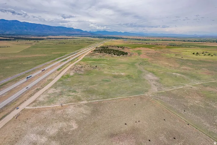 Expansive land featuring a highway, distant mountain range, and scattered vegetation