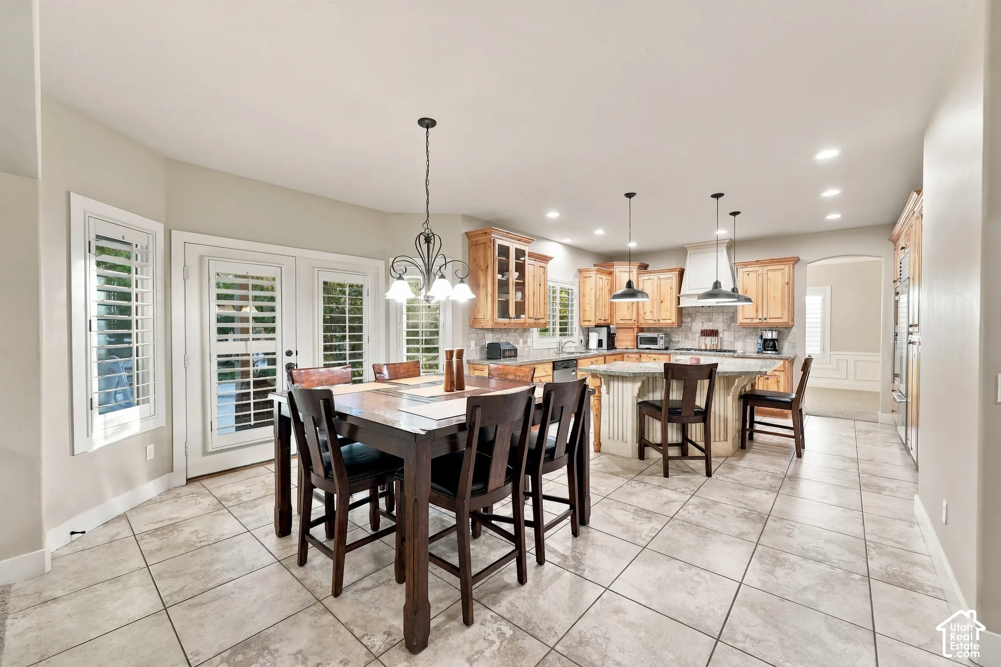 Spacious kitchen and dining area featuring tile flooring, light wood cabinetry, a center island with bar seating, and stainless steel appliances