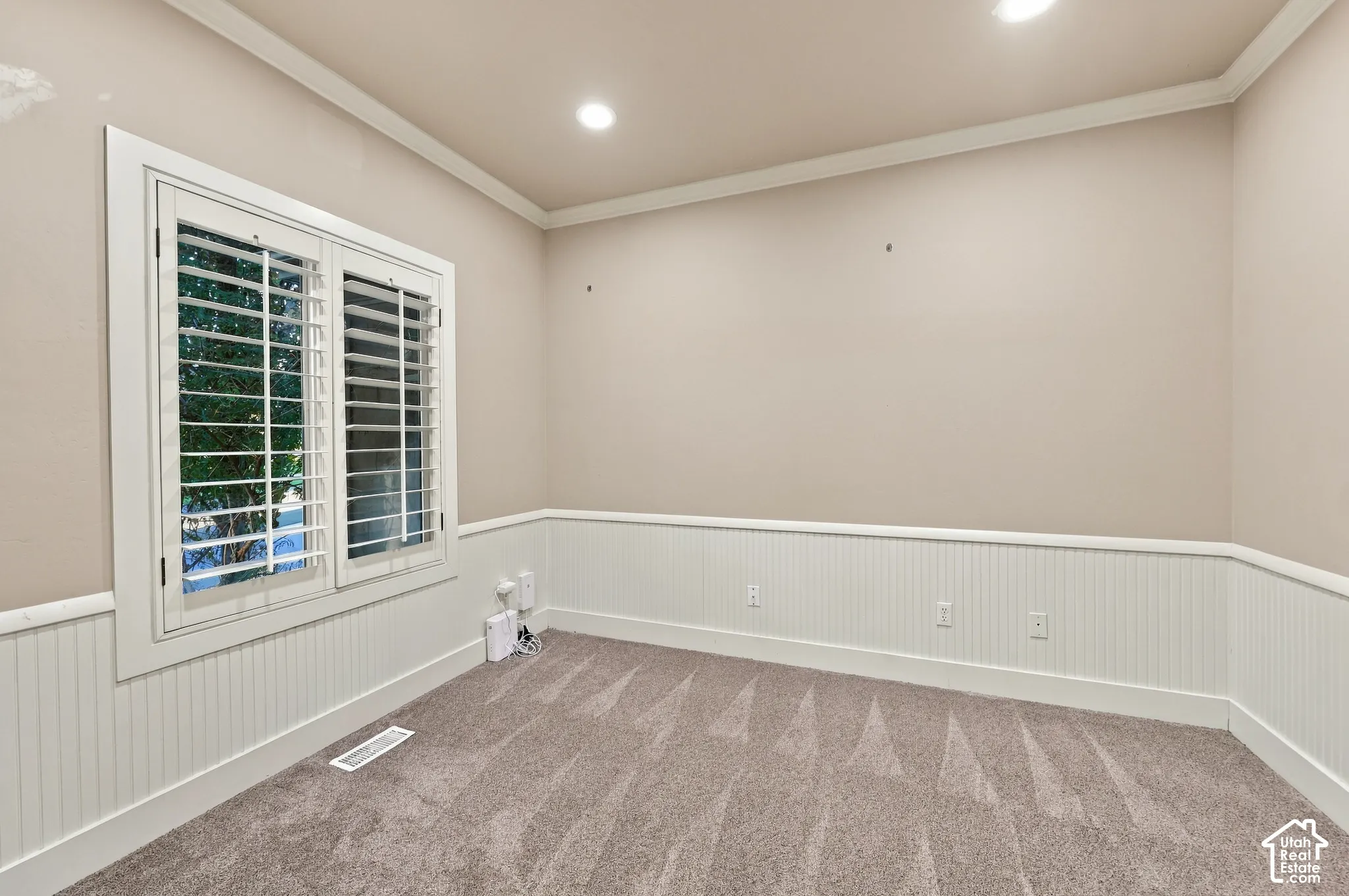 Recessed lighting, crown molding, white wainscoting, white interior window shutters, and carpeted flooring