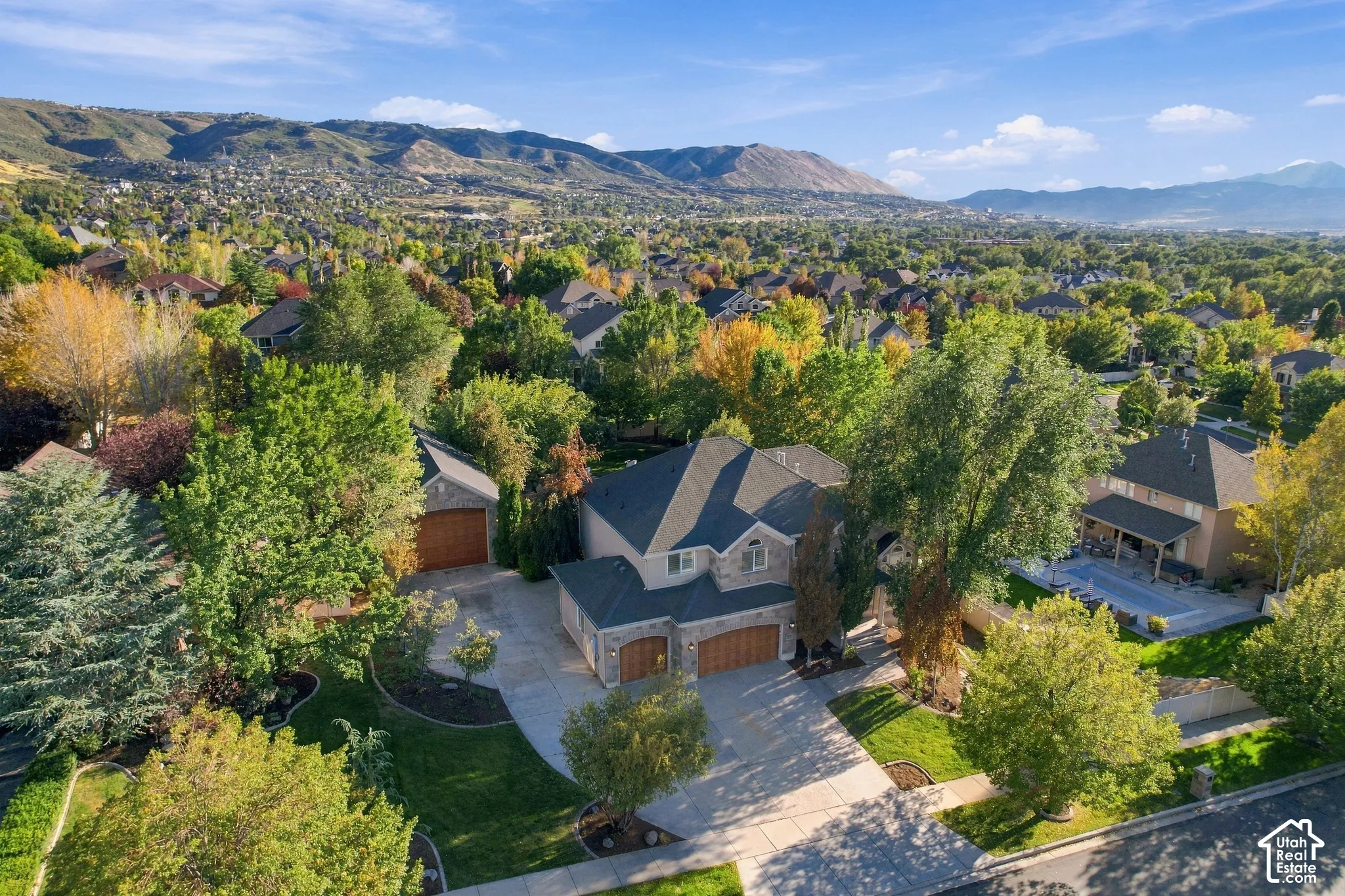 Stone exterior, multi-car garage, mature landscaping, paved driveway, mountain backdrop