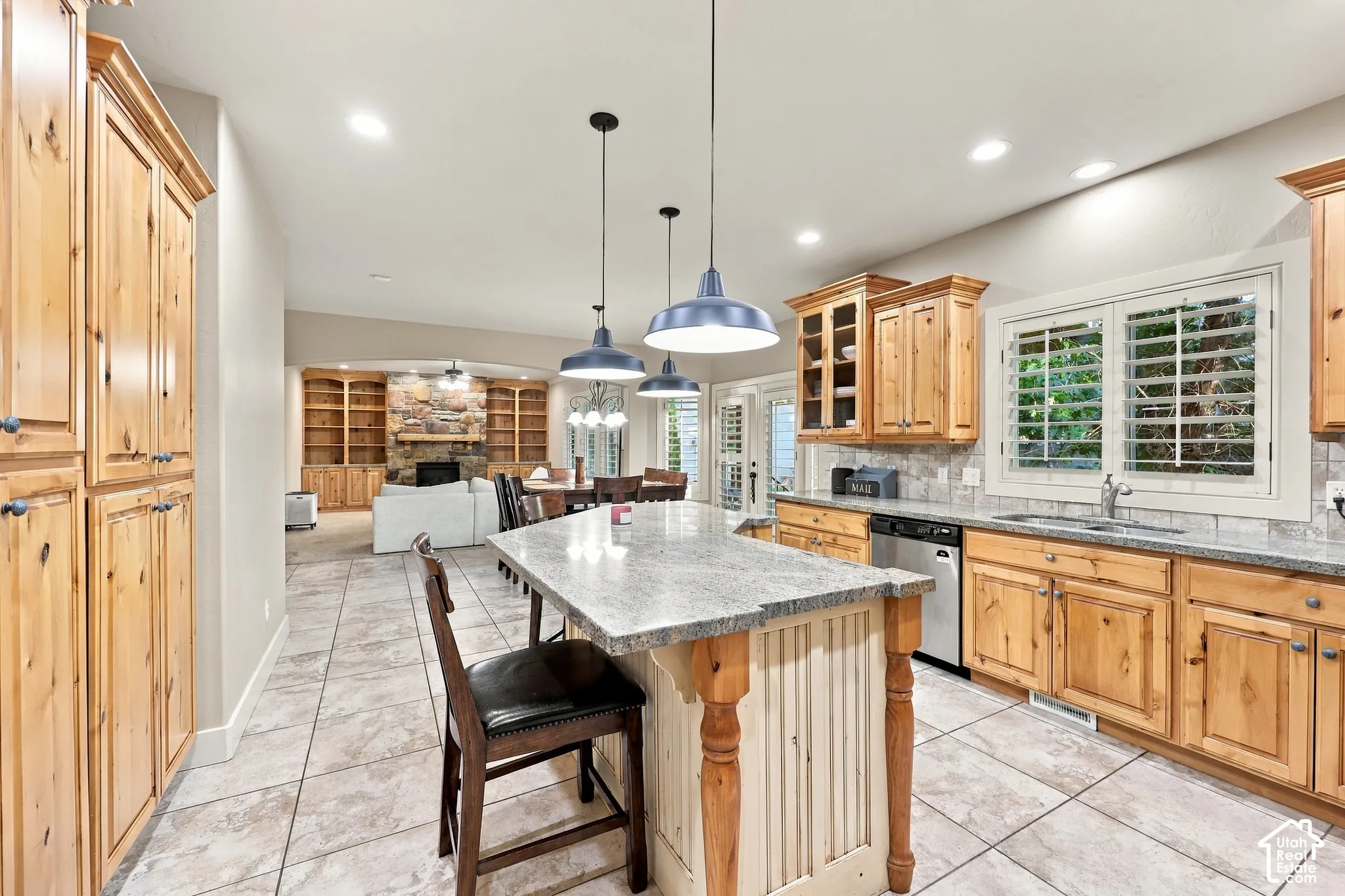 Kitchen featuring wood cabinetry, a center island with a light-toned countertop, tiled flooring, stainless steel appliances, and recessed lighting