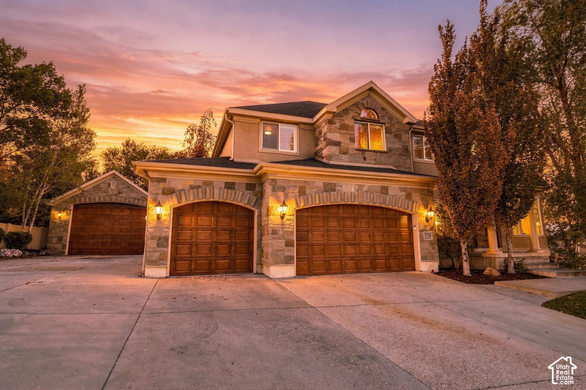 Stone veneer exterior with arched garage openings and decorative carriage lights