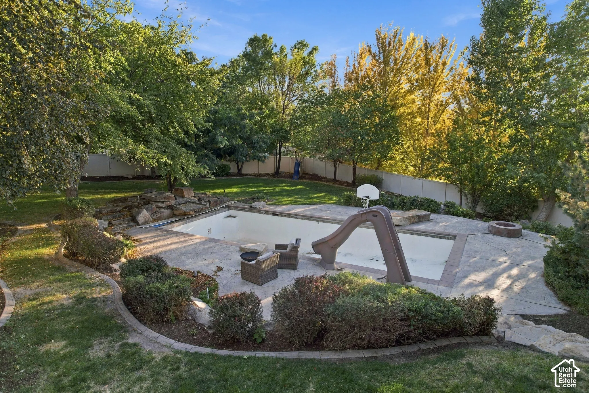 Expansive backyard featuring a swimming pool, integrated slide, stone patio, and a fire pit