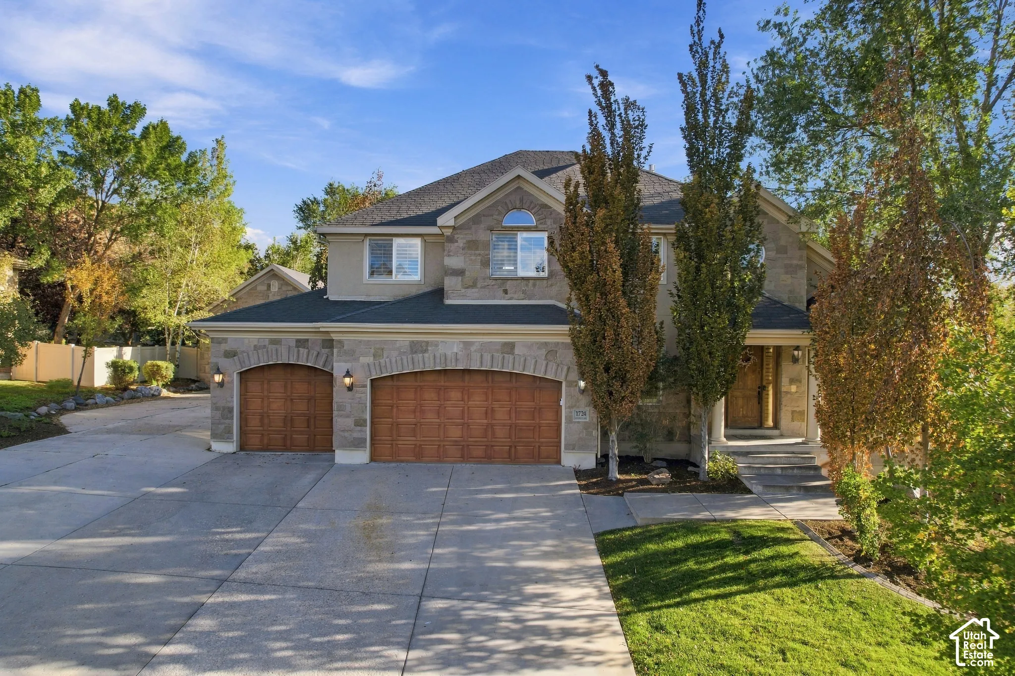 Stone and stucco exterior featuring an arched entryway and wood-finish garage doors