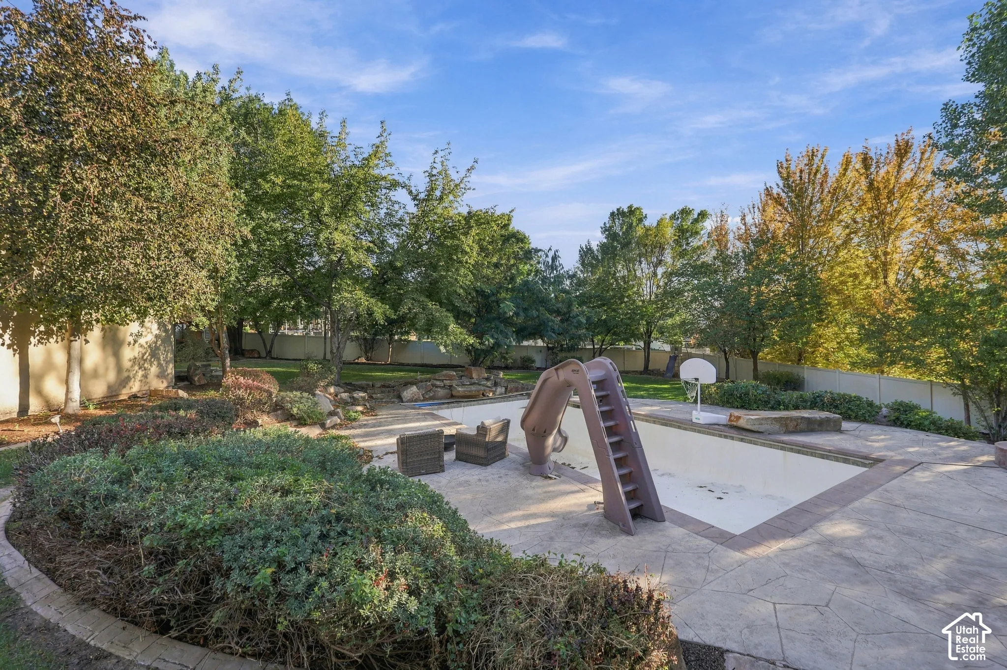 Expansive backyard with a large swimming pool, integrated slide, and a sports hoop
