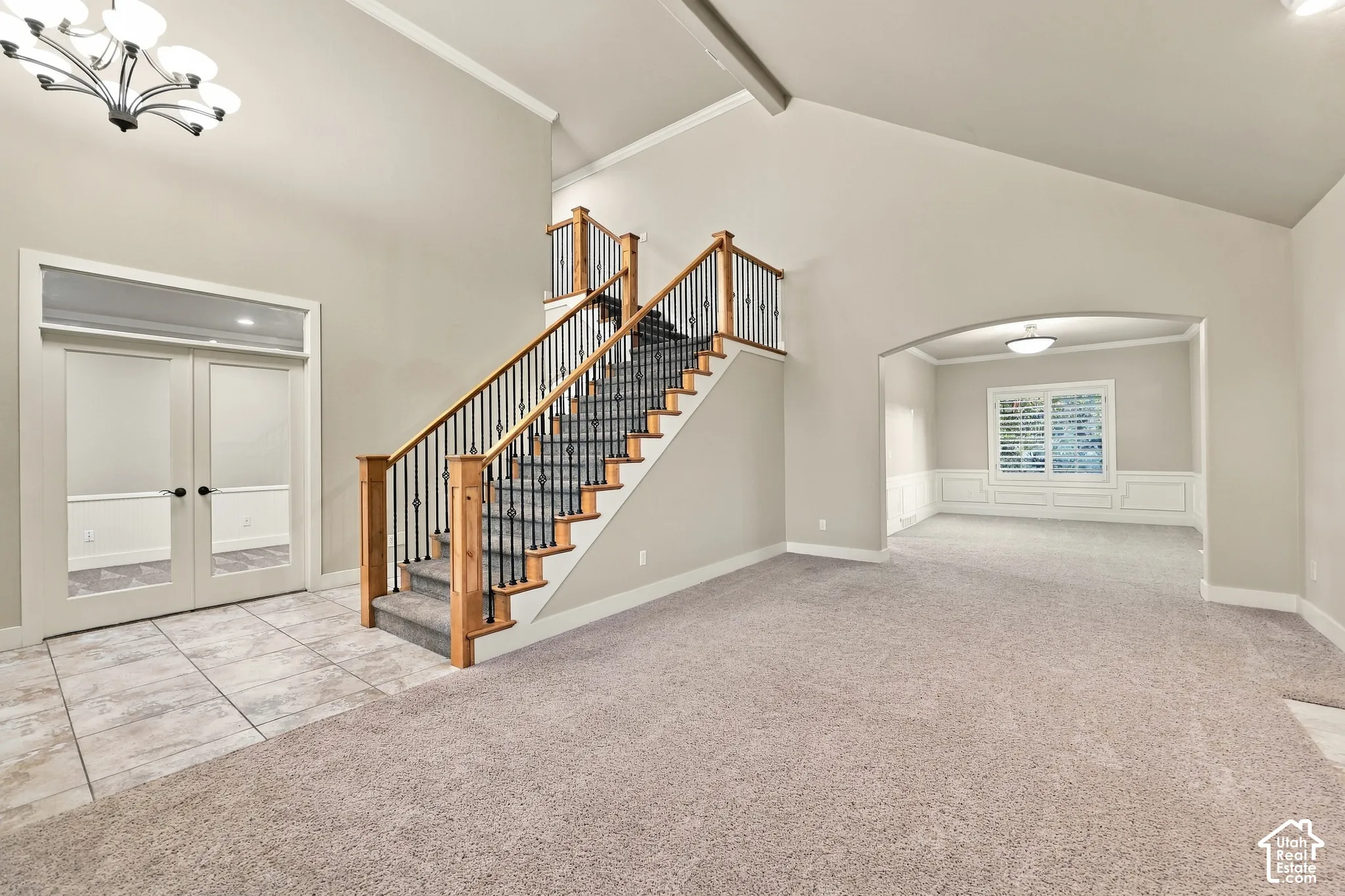 Grand entry with tile flooring, a prominent staircase featuring wood newel posts and wrought iron balusters, and a vaulted ceiling