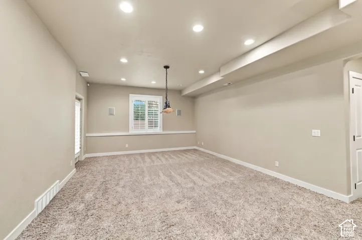 Recessed ceiling lighting, a decorative pendant light, white window shutters, and plush carpeting