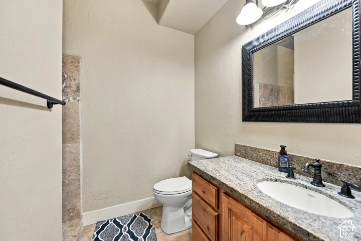 Vanity with a granite-style countertop, undermount sink, and dark-toned faucet
