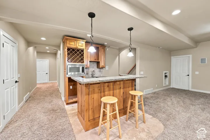 Built-in wet bar with wood cabinetry, integrated wine rack, and pendant lighting