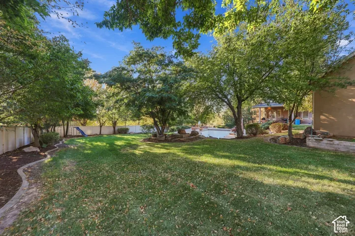 Expansive lawn area with mature trees, defined landscaping borders, and a privacy fence