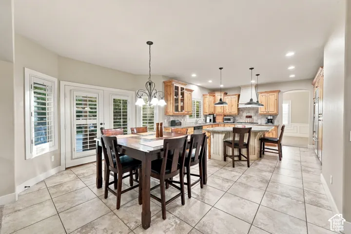 Spacious kitchen and dining area featuring tile flooring, light wood cabinetry, a center island with bar seating, and stainless steel appliances