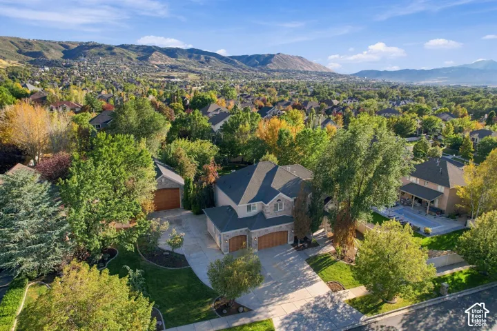 Stone exterior, multi-car garage, mature landscaping, paved driveway, mountain backdrop
