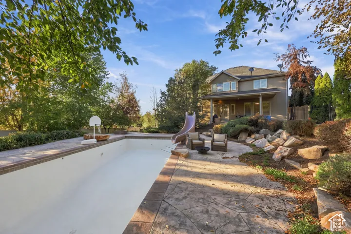 Two-story exterior with a covered patio, featuring an in-ground pool with a surrounding hardscape and a rock garden